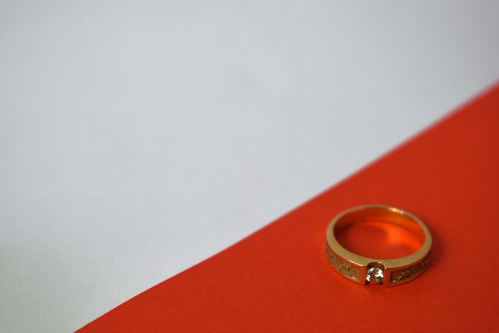 One diamond gold ring on duotone background with space for text