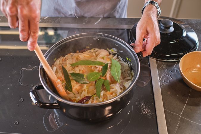Unrecognizable man standing at stove in process of cooking