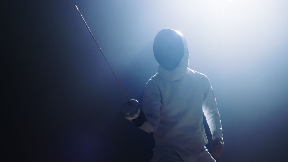 Fully Equipped Fencer Puts Lifts Foil Sword in Readiness for a Match.