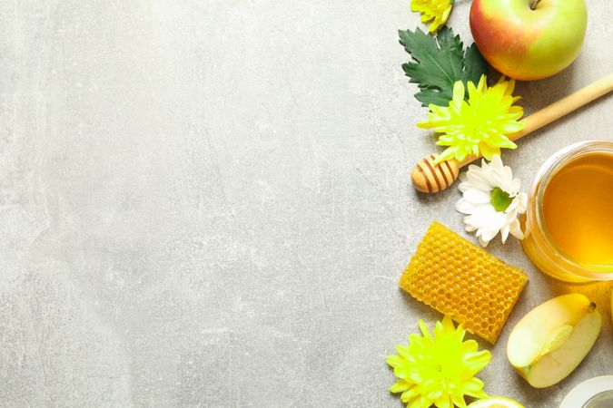 Flat lay with honey, flowers and fruits on grey background, copy space
