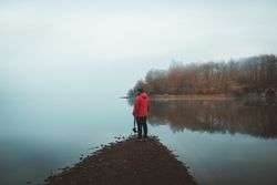Tourist on empty lake shore in fog