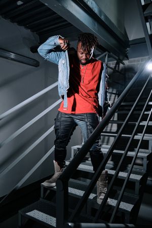 Black man putting on jacket on metal stairs