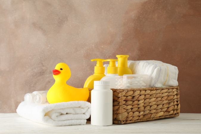 Baby hygiene accessories on wooden table against brown background