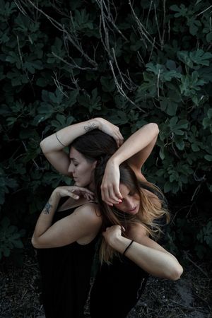 Young women posing near green bush