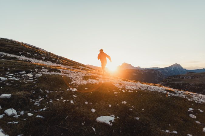 Man in red jacket hiking at sunset in Dolomites, Italy