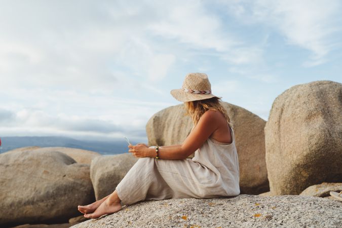Contemporary woman with phone chilling on seashore