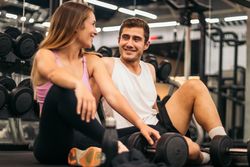 man and woman exercise workout in gym fitness breaking relax with dumbbell on the floor