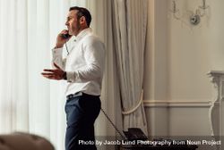 Man on business trip talking on hotel room phone 5lLDM5