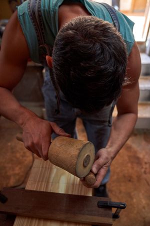 Unrecognizable sculptor working with wooden detail