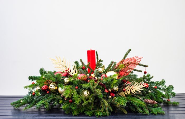 Side view of Christmas table center piece with candle, pine and ornaments