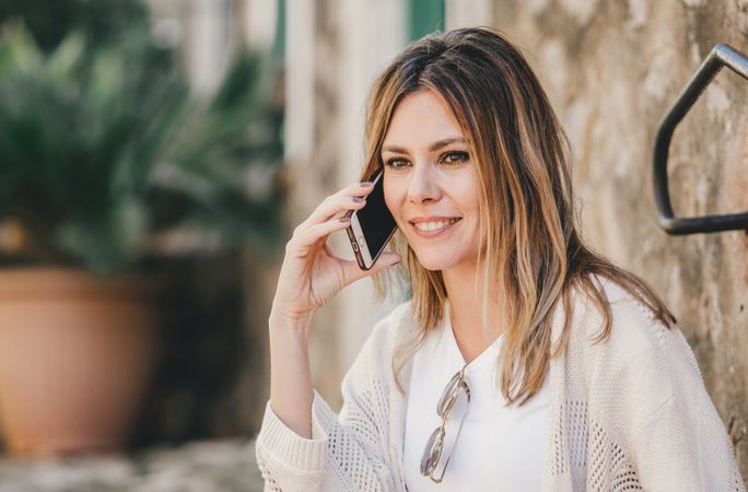 Woman with smartphone sitting on stone steps of stairs