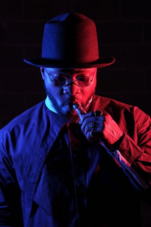 Black male smoking hookah in dark studio
