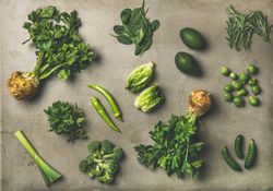 Arrangement of fresh green garden vegetables on concrete surface