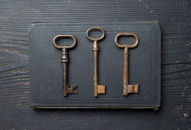 Vintage Keys over dark leather book cover and wooden table