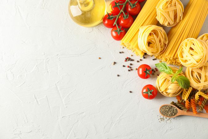 Composition with pasta, tomatoes, spices and olive oil on bright background, space for text