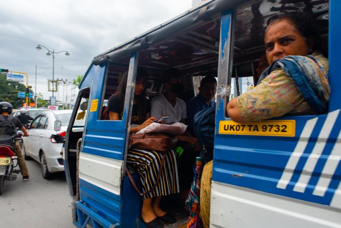 Adult Indian woman looking out of cramped transit bus in traffic in Dehradun, India