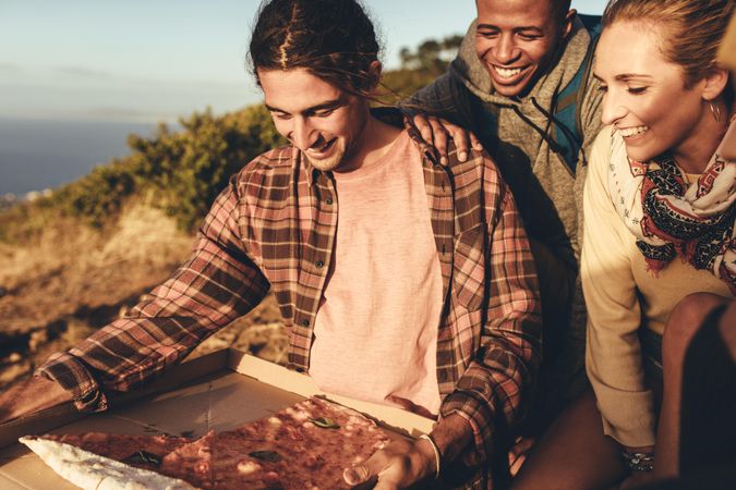 Group of hikers having pizza on top of mountain