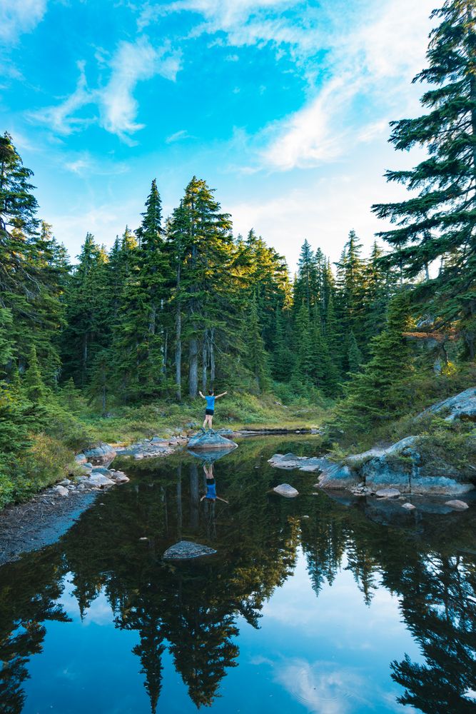 Person opening their arms and standing on rock in a river