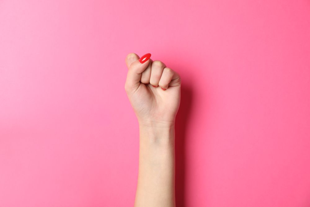 Woman hand with red nails on pink background, space for text