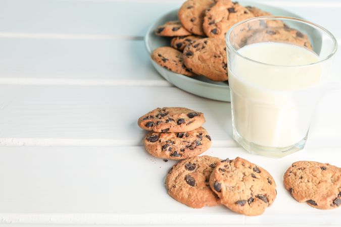Tasty chocolate chip cookies and glass of milk on wooden table. Space for text
