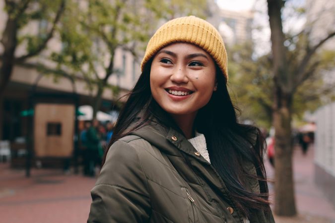 Smiling young Asian woman in yellow beanie and jacket