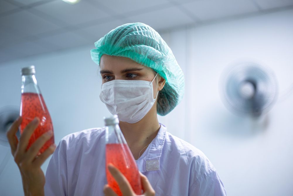 Woman worker inspecting on juice bottle at factory