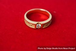 Man's diamond gold ring on red background with copy space 56Gvrl