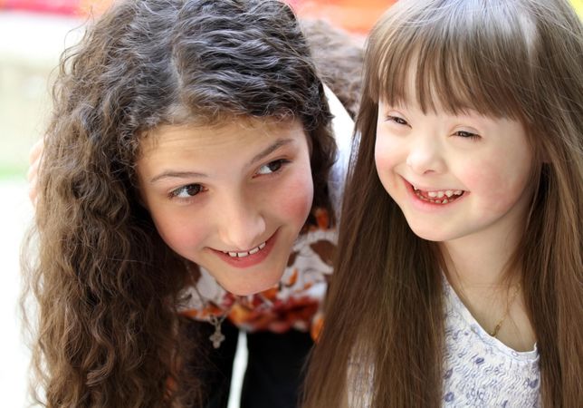 Happy young girl with Down syndrome and her teenage  sister
