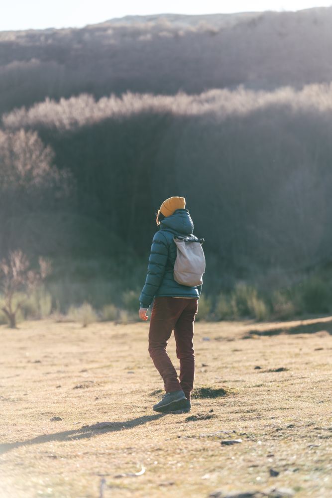 Traveler with backpack walking on autumn field