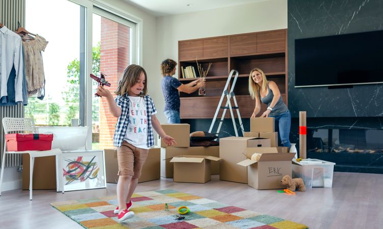 Boy playing with toy airplane while parents unpack