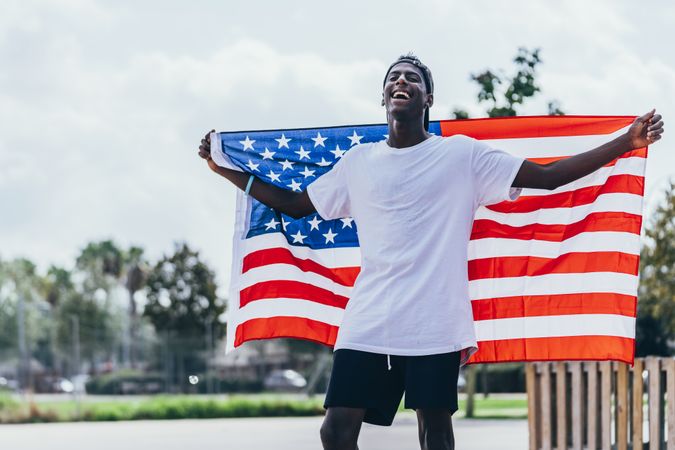 Black man wrapped in American Flag outside