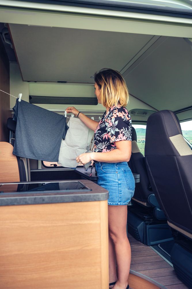 Vertical shot of female hanging laundry in small motorhome kitchen
