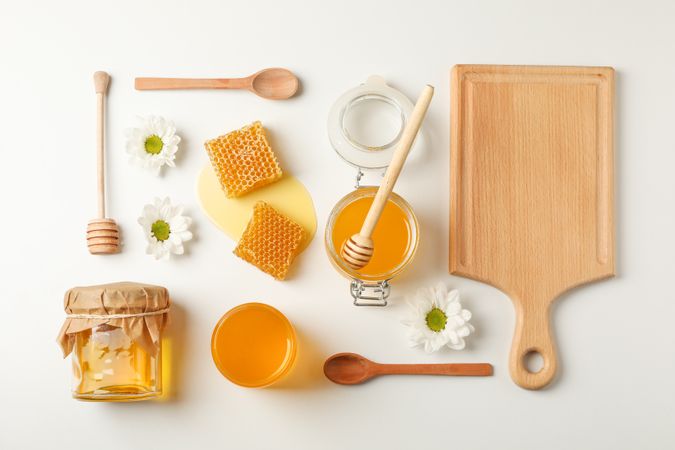 Flat lay. Honey, dipper, spoon and board on neutral background, space for text