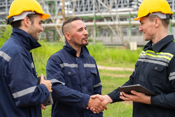 Engineer worker hand shaking to colleagues team for success work at construction site of petroleumchemical industry or refinery oil plant factory