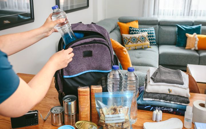 Woman putting a water bottle to prepare emergency backpack