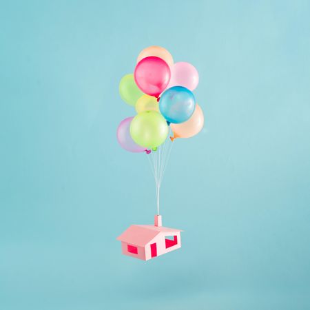 Colorful balloons with pink house flies in the blue sky