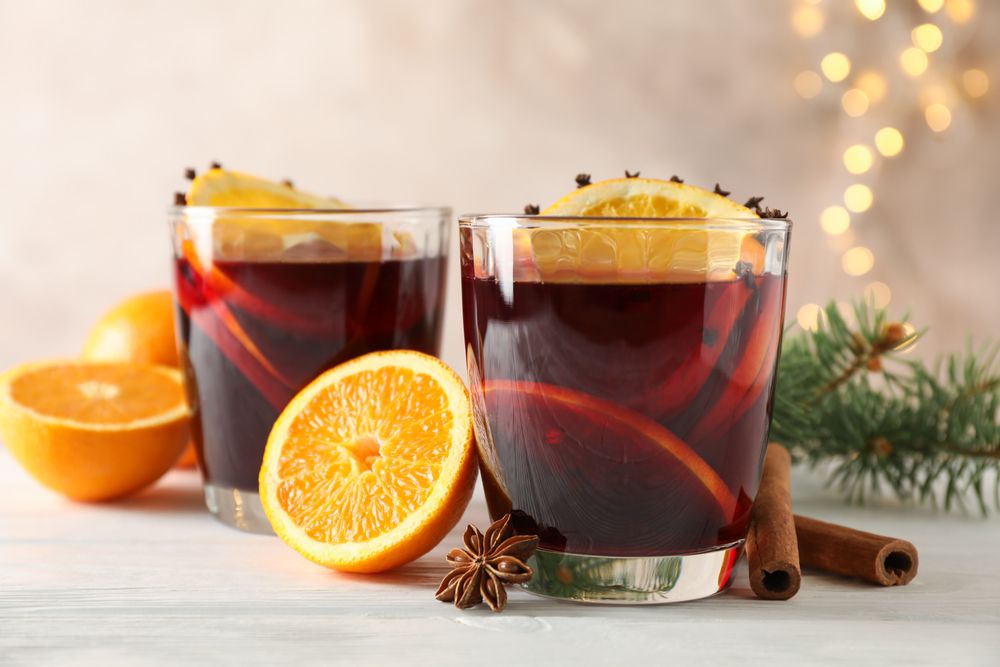 Glasses of tasty mulled wine with orange on wooden background, space for text