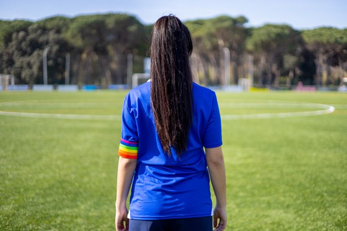 Female soccer player with captain armband with LGBT pride flag on pitch