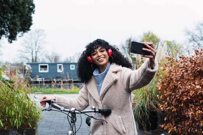 Black woman with smartphone on bicycle