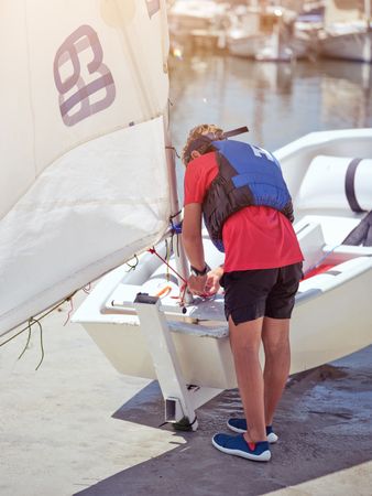 Male traveler with yacht near water