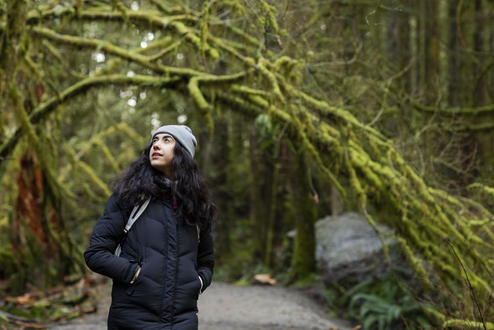 Young female looking up to her left while taking a hiking break in woods