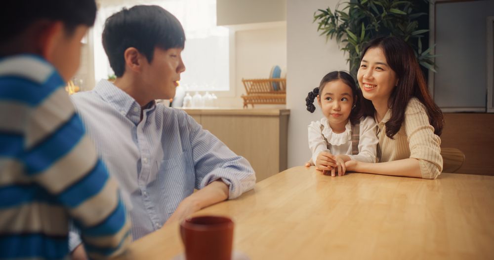 Portrait of Happy Small Korean Family Talking Together in Their Sunny Home.