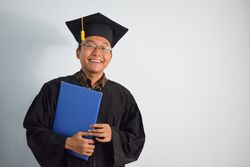 Happy male graduate in studio shoot holding certificate
