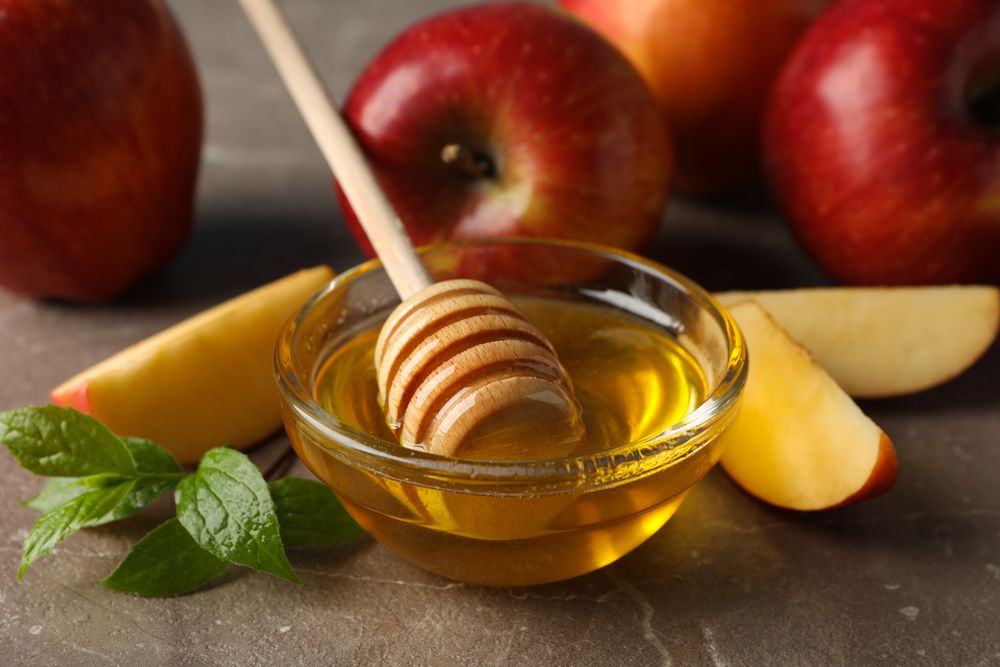 Close up side view of apples and honey in kitchen