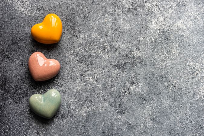 Thee colorful ceramic heart ornaments on grey counter