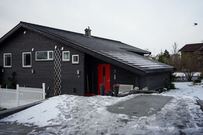 Large barn against snowy hill and residential houses in countryside