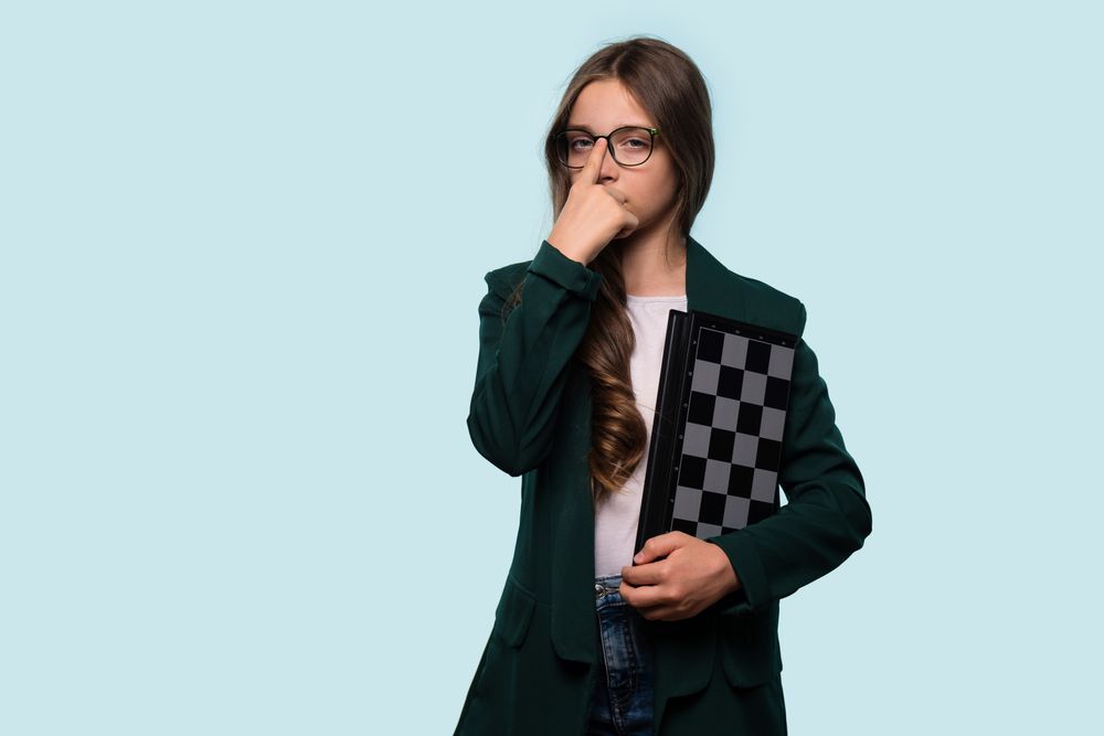 Teen girl holding chessboard, wearing glasses