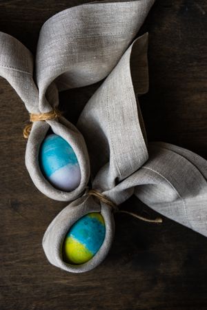 Close up of two Easter eggs wrapped with rabbit ears with napkin
