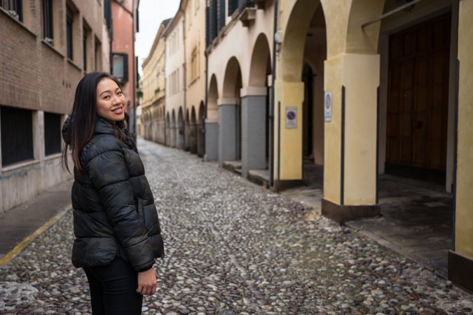 Curious female tourist strolling at old city street on overcast weather