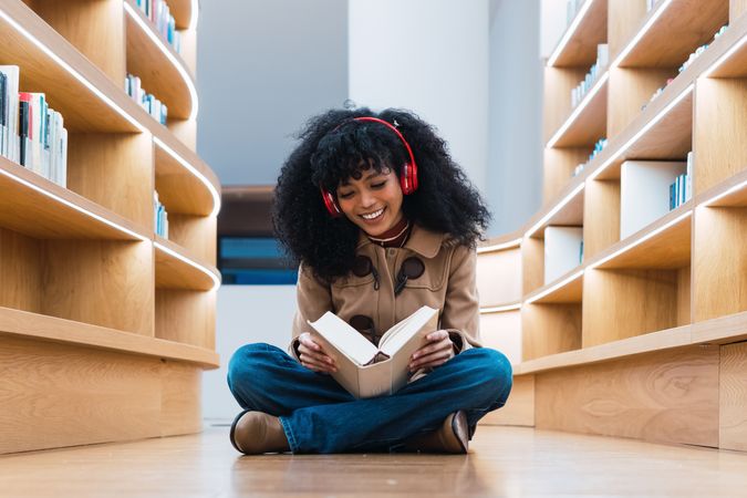 Glad Black female reading book in library